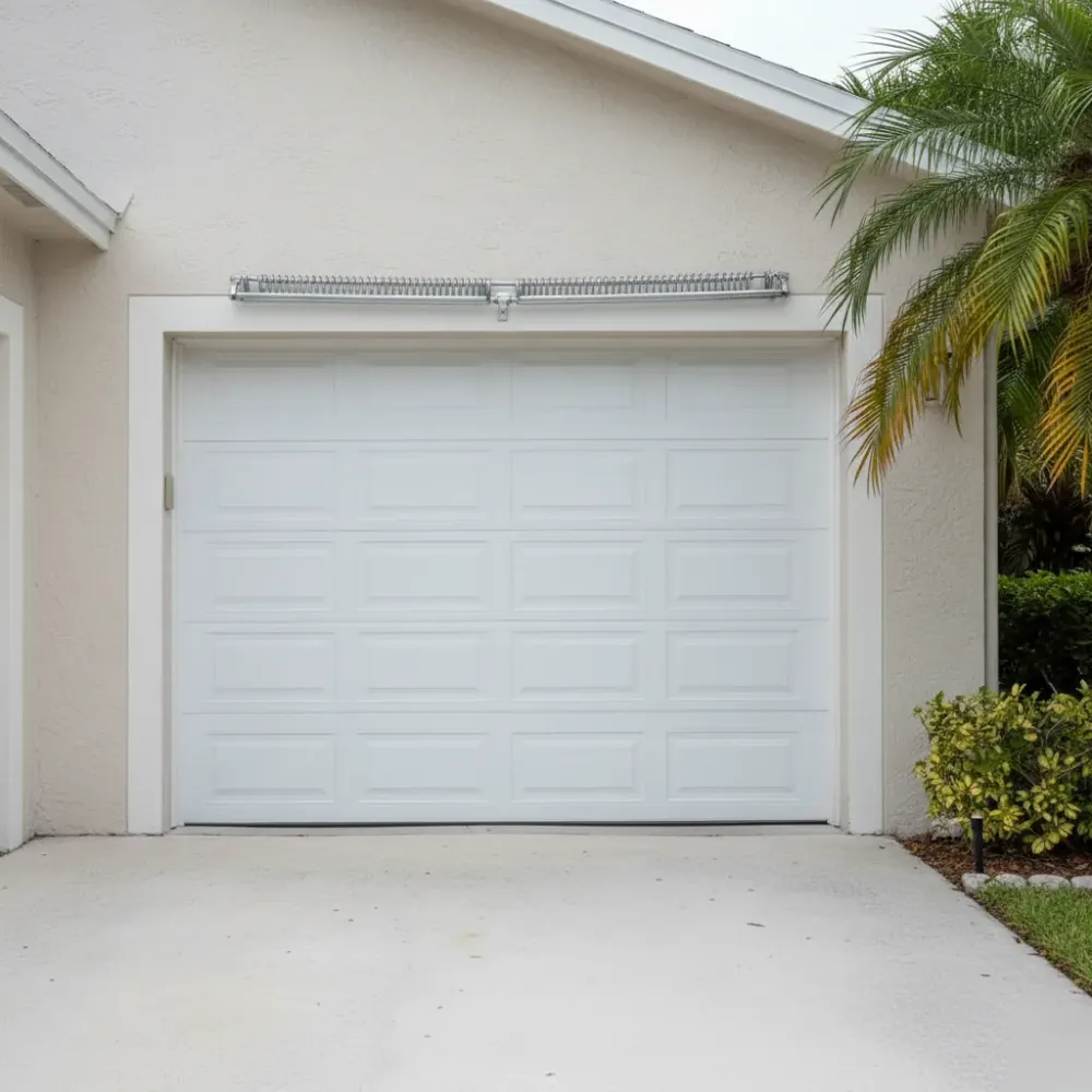 Fully closed white garage door with new torsion springs on a stucco home in Hallandale Beach after emergency repair.
